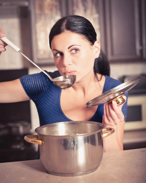 Jonge huisvrouw kookt voedsel in keuken — Stockfoto