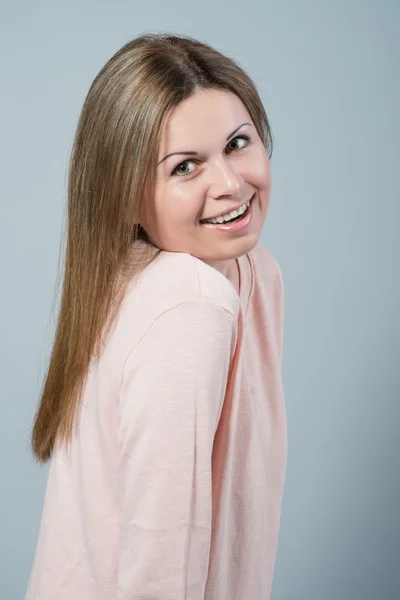 Mujer joven sonriendo sobre fondo gris — Foto de Stock