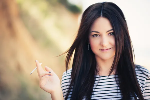 Beautiful young woman who smokes a cigarette — Stock Photo, Image