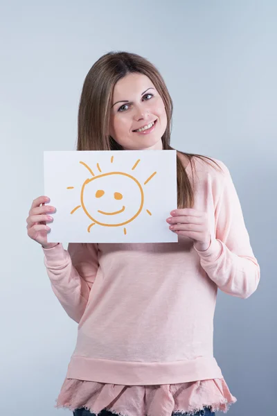 Junge Frau hält einen Karton mit einer Sonne in der Hand — Stockfoto