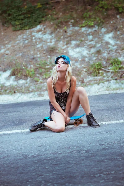 Jovem mulher sentada sobre um skate — Fotografia de Stock