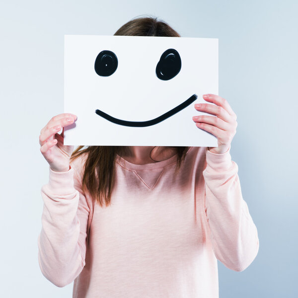 woman holding a cardboard with a smiley face