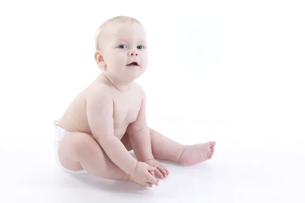 Bebê-menino sorridente em uma fralda sentada no chão — Fotografia de Stock