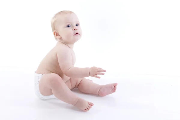 Niño sonriente en un pañal sentado en el suelo —  Fotos de Stock