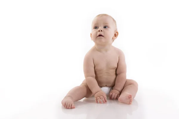 Bebê-menino sorridente em uma fralda sentada no chão — Fotografia de Stock