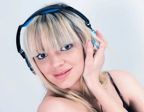 Menina atraente ouvir música com fone de ouvido azul — Fotografia de Stock