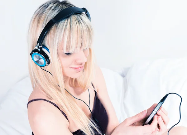 Linda chica rubia escuchando música en su teléfono inteligente — Foto de Stock