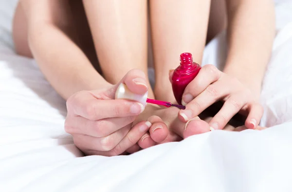 Close up woman brushing her nails in the red color