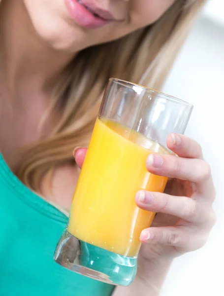 Menina atraente beber uma laranja em uma cozinha — Fotografia de Stock