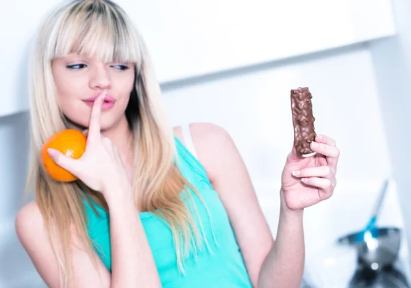 Diet hesitating between a candy bar and an orange — Stock Photo, Image