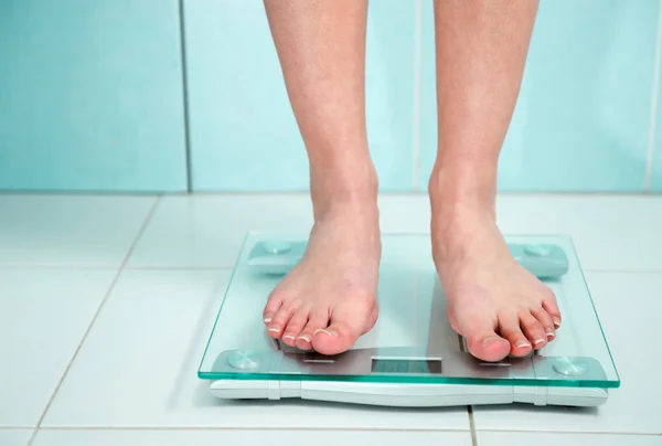 Primer plano de los pies de mujer que pesan en el baño Imagen de stock