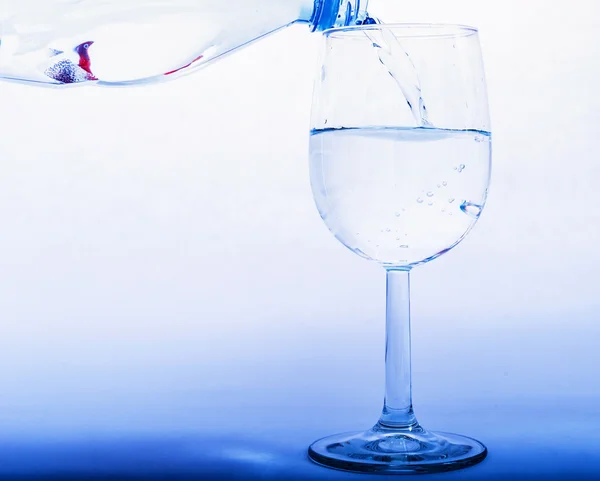 Drinking water is poured from a bottle into a glass — Stock Photo, Image