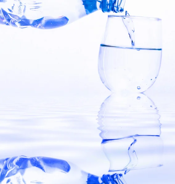 Trinkwasser wird aus einer Flasche in ein Glas gegossen — Stockfoto