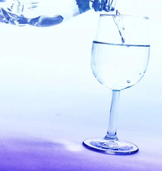 Drinking water wordt uit een fles gegoten in een glas — Stockfoto