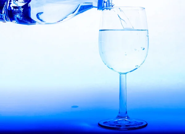 Drinking water is poured from a bottle into a glass — Stock Photo, Image