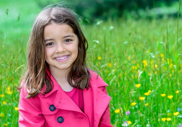 Glückliches süßes Kind sitzt in einem Blumengarten — Stockfoto