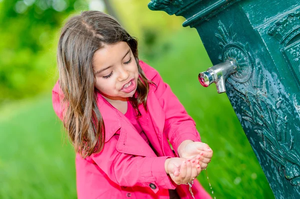 Petite fille buvant de l'eau dans une fontaine — Photo