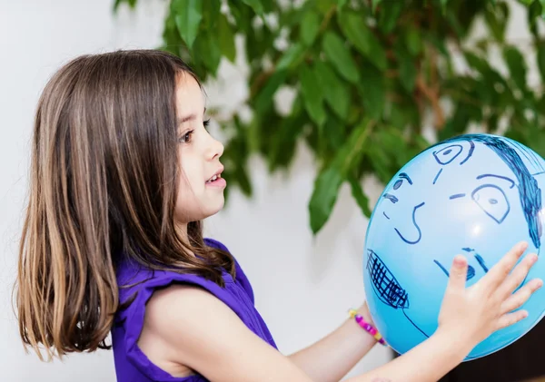Porträt eines hübschen jungen Mädchens, das mit einem blauen Luftballon spielt — Stockfoto
