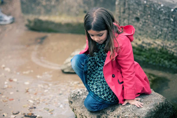 Pretty little girl playing on a rock at the water's edge — Stock Photo, Image