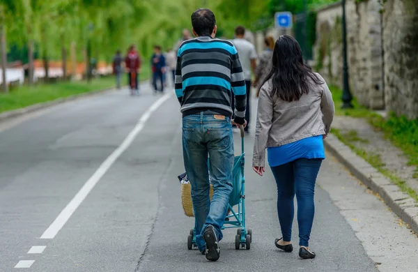 Couple walking with a baby stroller — Stock Photo, Image