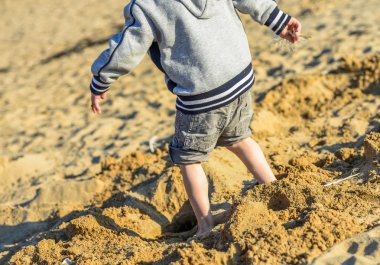 Deniz kenarında kumda oynayan genç çocuk