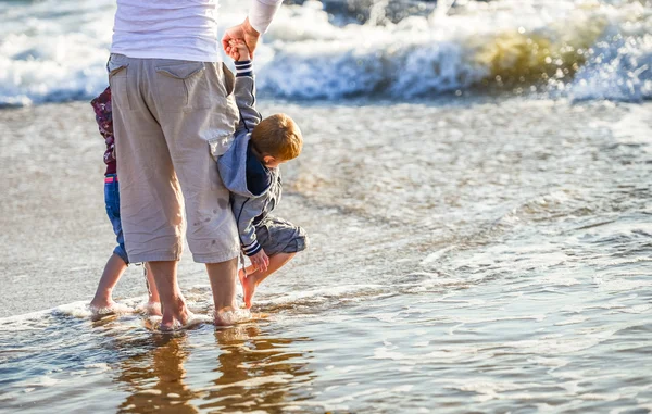 Duas crianças e seu pai brincando em frente ao oceano — Fotografia de Stock