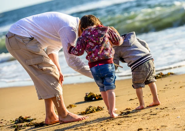 Duas crianças e seu pai brincando em frente ao oceano — Fotografia de Stock