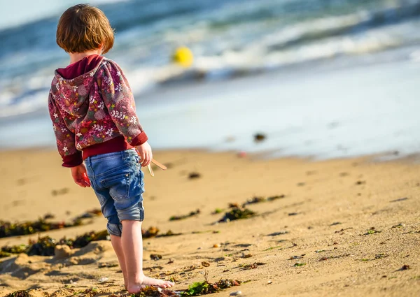 Un giovane bambino carino in piedi di fronte all'oceano — Foto Stock