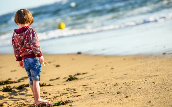 Un giovane bambino carino in piedi di fronte all'oceano — Foto Stock
