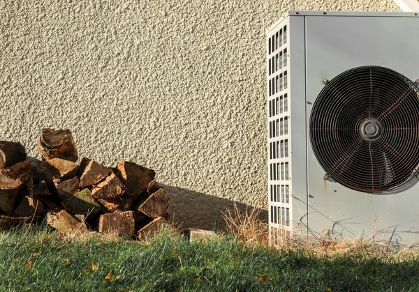 Brennholzstapel und Klimaanlage in der Nähe einer Mauer — Stockfoto