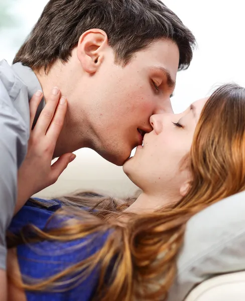 Attractive couple of lovers kissing itself lovingly on a sofa — Stock Photo, Image