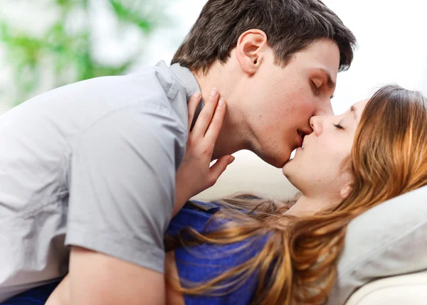 Attractive couple of lovers kissing itself lovingly on a sofa — Stock Photo, Image