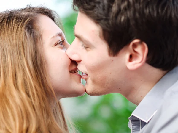 Casal atraente de amantes beijando-se amorosamente em um sofá — Fotografia de Stock