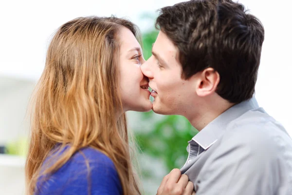 Casal atraente de amantes beijando-se amorosamente em um sofá — Fotografia de Stock