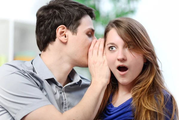 Man whispering in the ear of his surprised wife — Stock Photo, Image