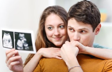 Beautiful couple watching with emotion ultrasound pictures of their baby clipart