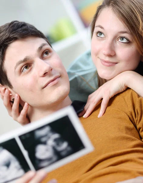 Leuk paar verbeeldt de toekomst van hun ongeboren kind met echografie foto's in handen — Stockfoto