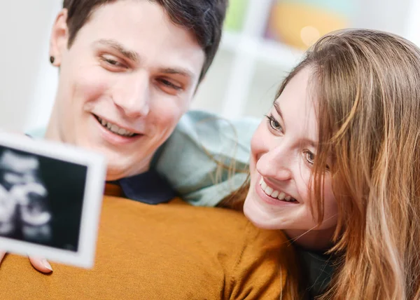 Beautiful couple watching with emotion ultrasound pictures of their baby — Stock Photo, Image