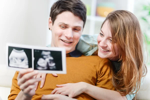 Bebeklerinin ultrason fotoğraflarıyla seyreden güzel bir çift. — Stok fotoğraf