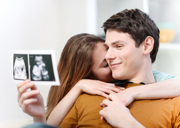 Beautiful couple watching with emotion ultrasound pictures of their baby