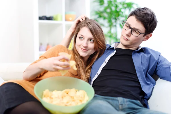 Belo jovem casal assistindo TV e comer em um sofá — Fotografia de Stock