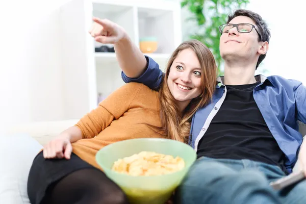 Lachen paar genieten van lettend op een film thuis op de Bank — Stockfoto