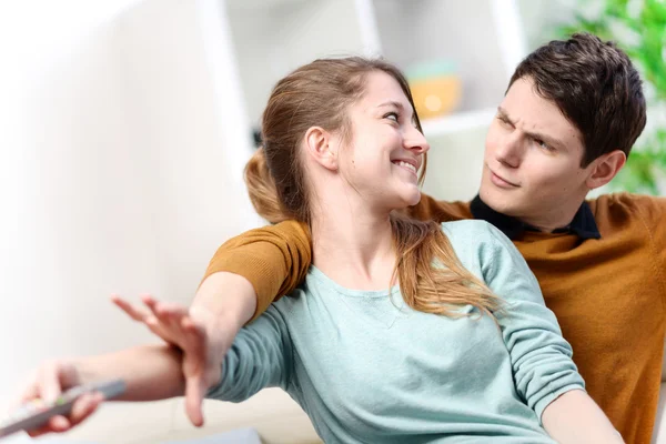 Beautiful couple bickering to change tv channel on remote control — Stock Photo, Image