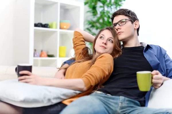 Preciosa pareja viendo la televisión mientras beben té en su sala de estar —  Fotos de Stock