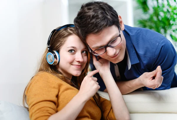 Atractiva pareja joven escuchando música juntos en su sala de estar en casa — Foto de Stock