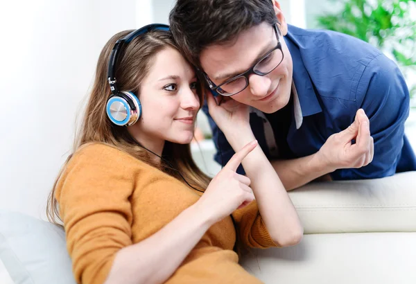 Atractiva pareja joven escuchando música juntos en su sala de estar en casa — Foto de Stock