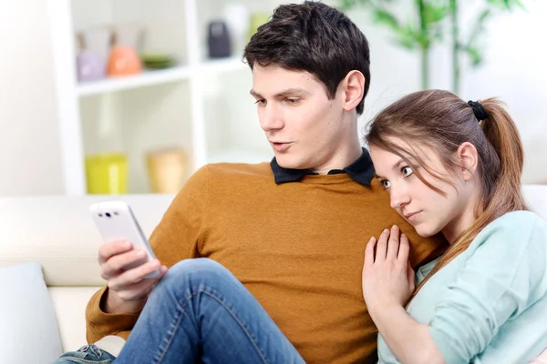 Atractivo joven casado viendo una pantalla de la celda en la sala de estar —  Fotos de Stock