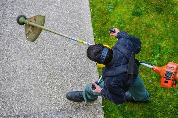 Jardinero usando cortador de cuerdas con cable en un parque — Foto de Stock