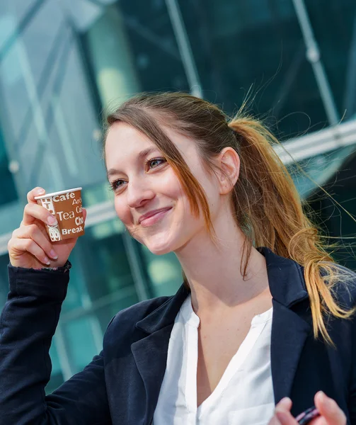 Junior executive having a coffee break in front of her company — Stock Photo, Image