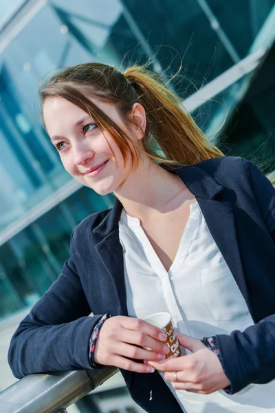 Junior executive having a coffee break in front of her company — Stock Photo, Image